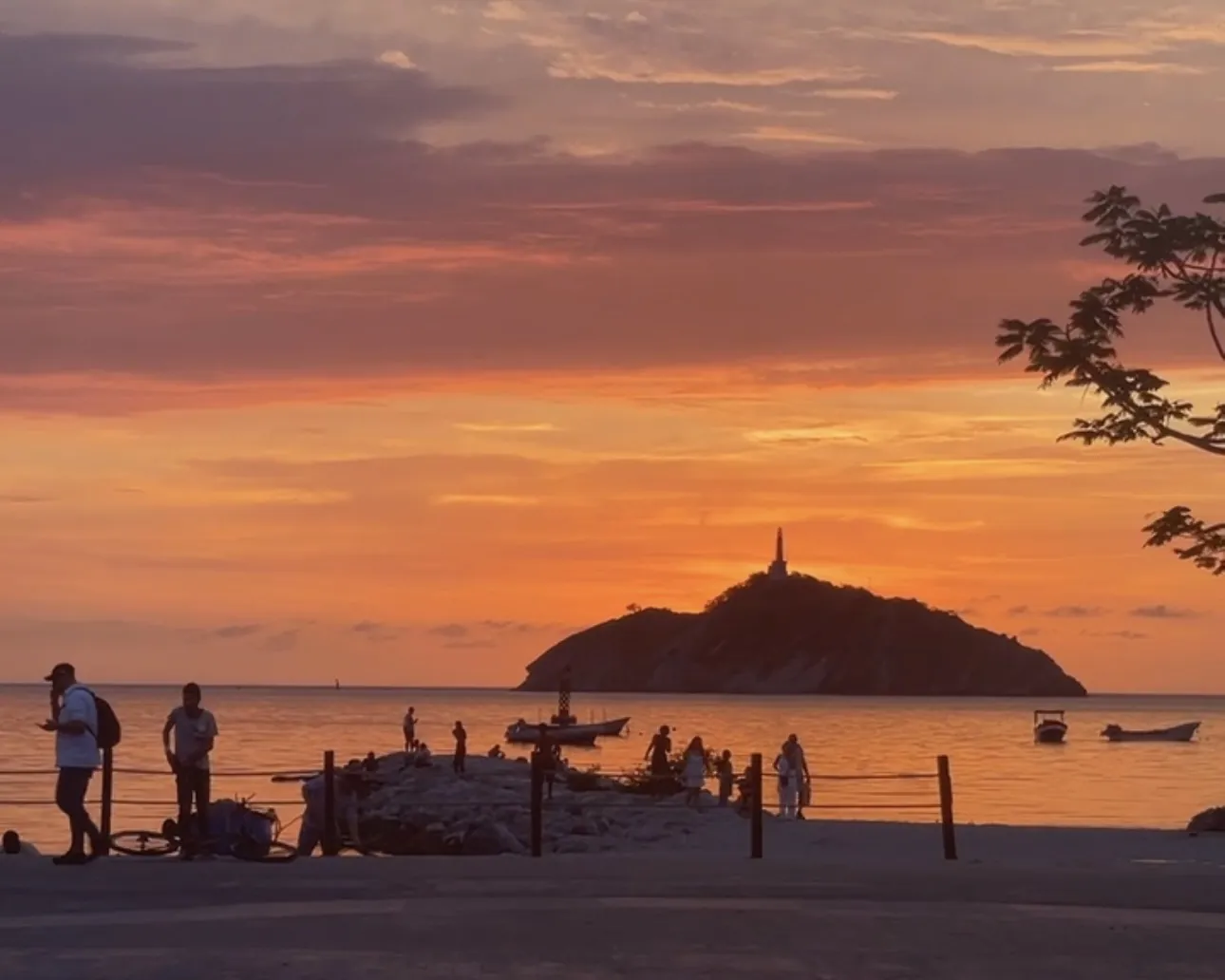 Atardecer sobre la bahía de Santa Marta con El Morro y siluetas de paseantes