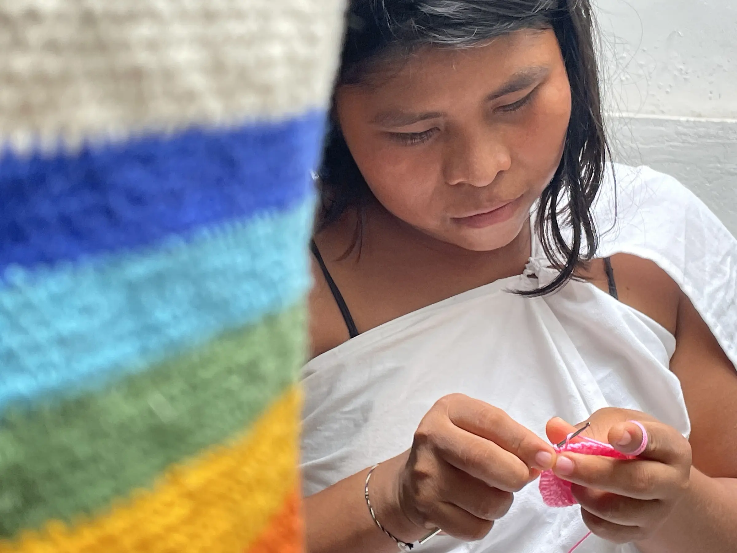 Artesana indígena tejiendo una mochila a crochet durante la experiencia Tejiendo Vida