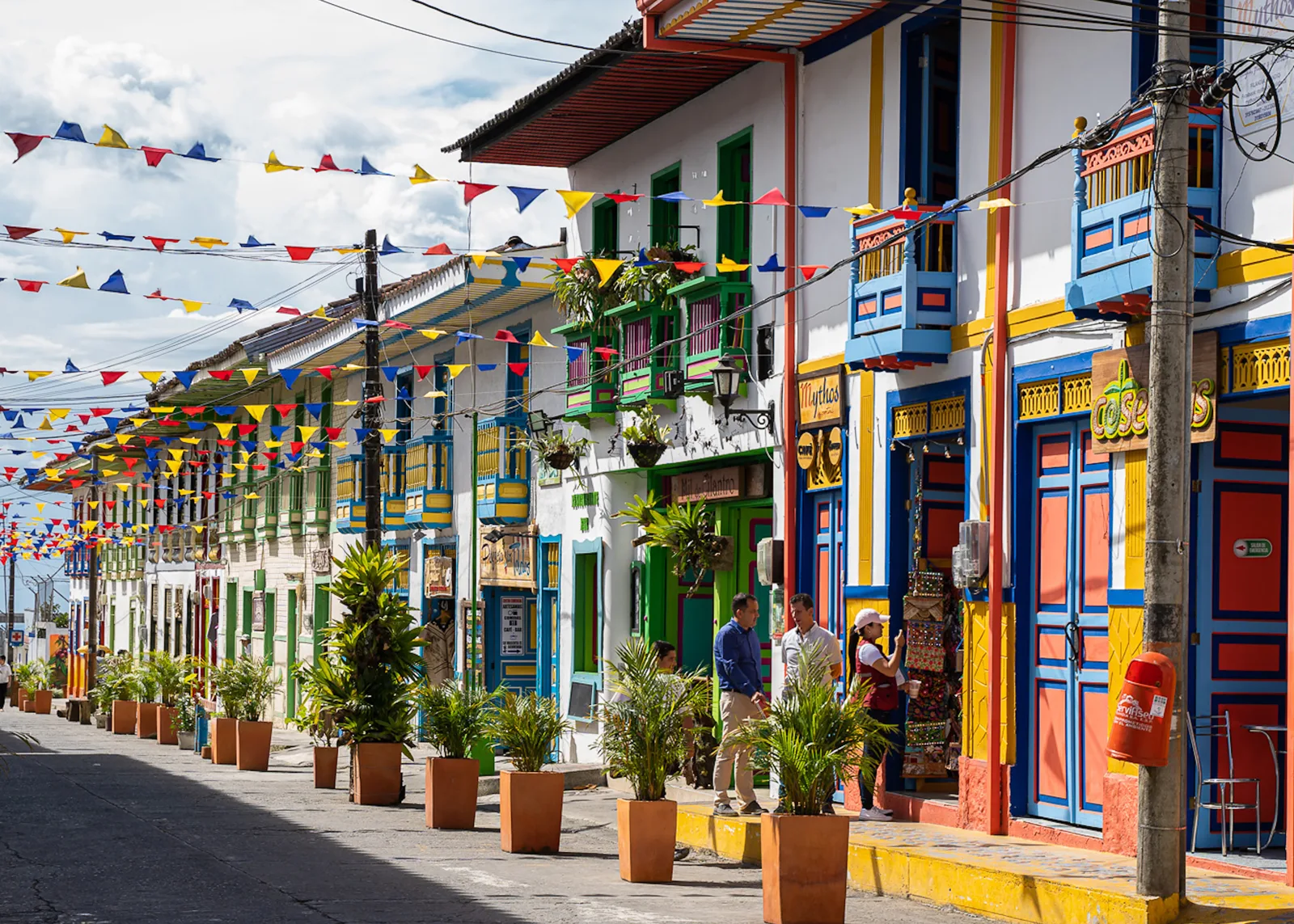 Travelers walking along a colourful street in Filandia, Coffee Region, Colombia, decorated with festive flags